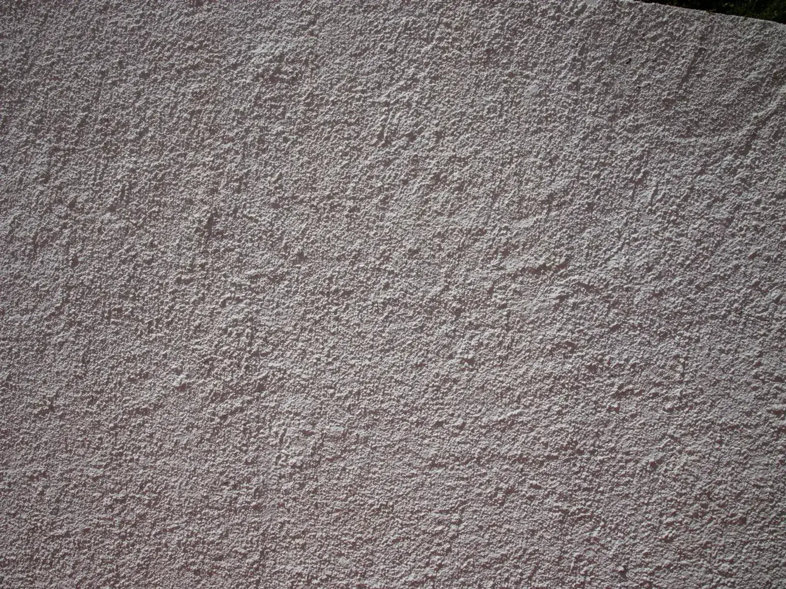 Close-up of a through-coloured thin-coat render on an external wall, showing its even scraped texture.